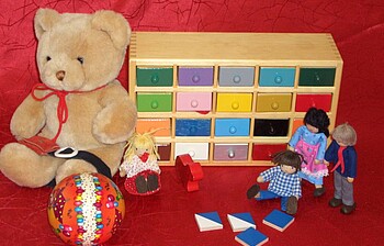 Verschiedenes Spielzeug, darunter ein Bär, ein Ball und kleine Holzpüppchen
