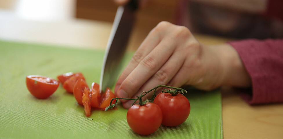 Tomaten werden mit einem Messer kleingeschnitten