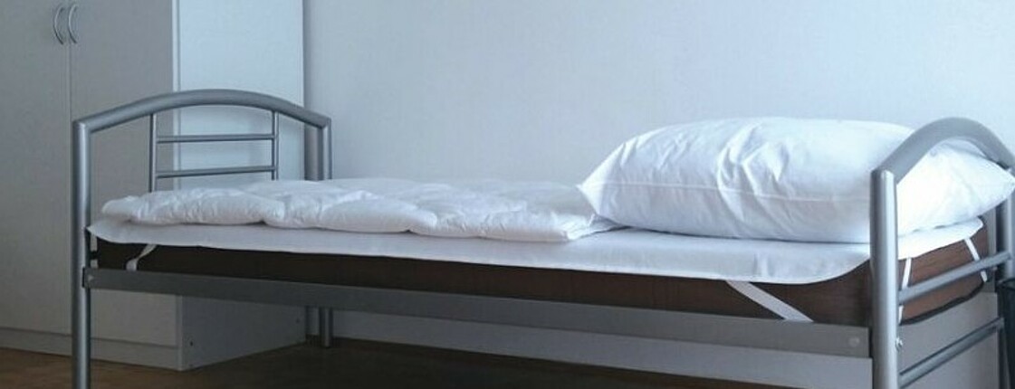 Ausschnitt eines Zimmers mit Bett und Kasten